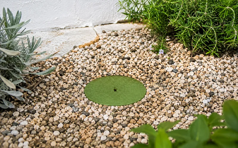 Estació de terra enterrada al jardí amb tapa verda circular